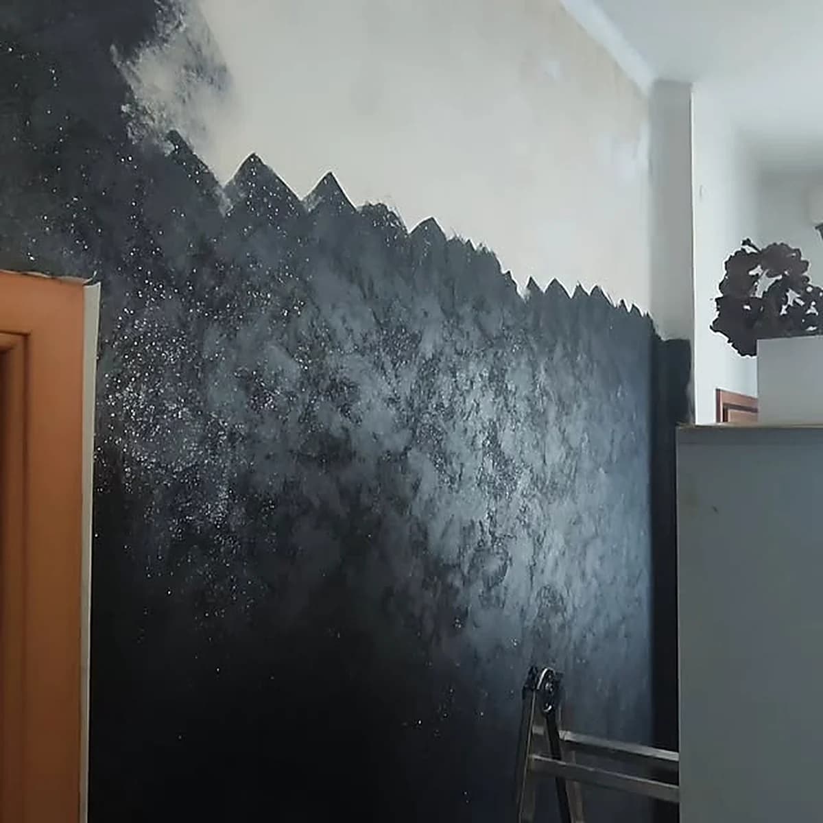 Dettaglio del bordo frastagliato di una parete decorativa nera con finitura a spatola