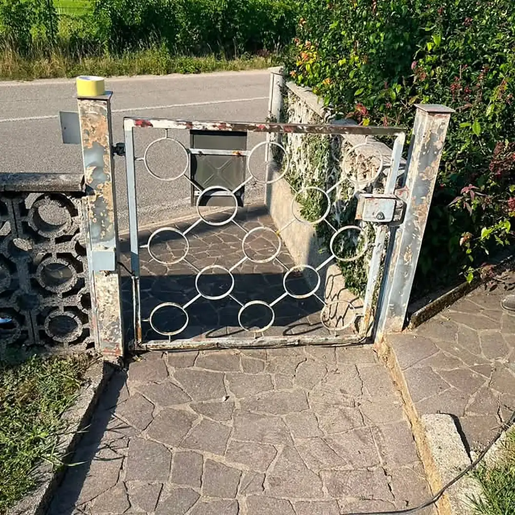 Cancello in ferro battuto con decori circolari durante la verniciatura, in giardino