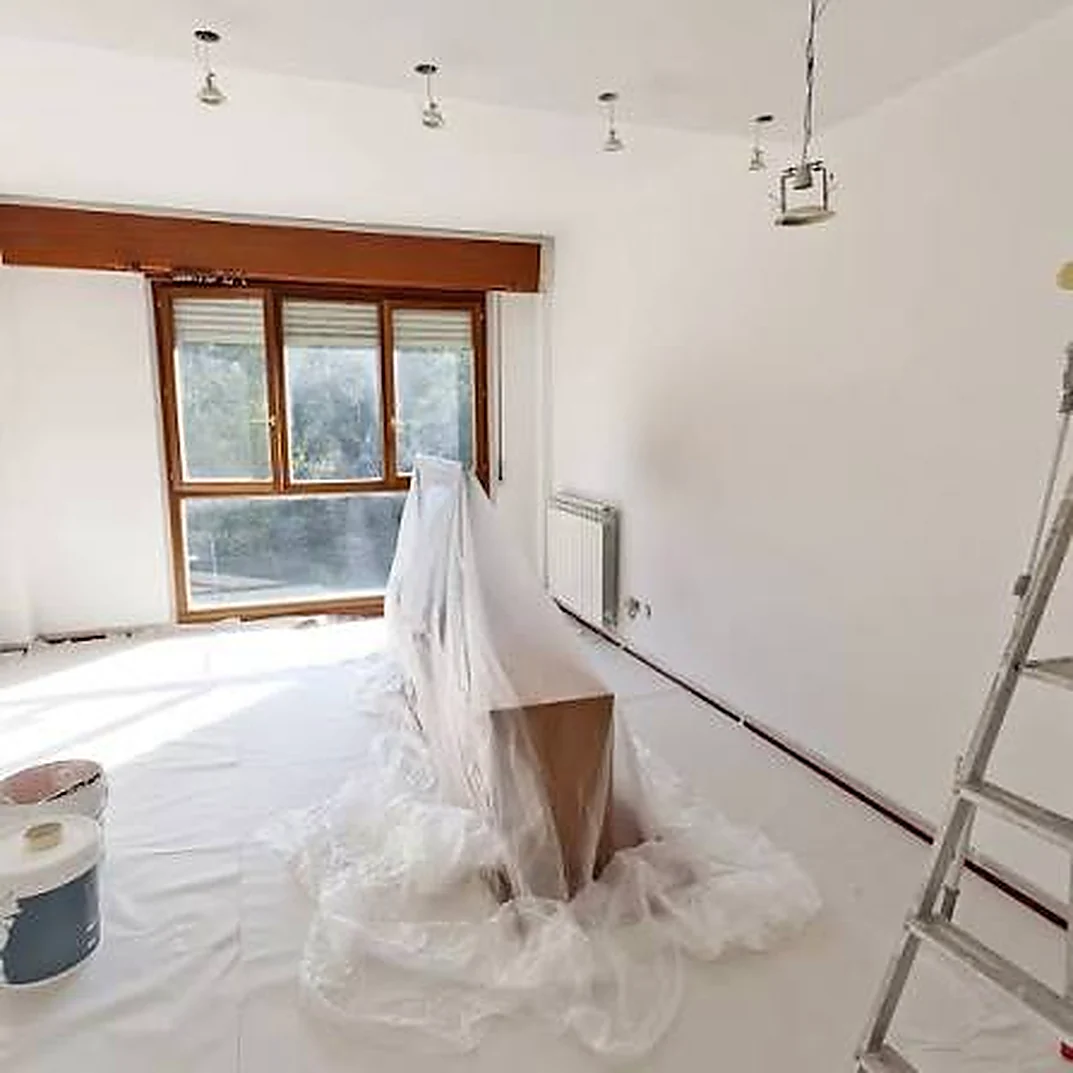 Soggiorno con mobili coperti dai teli e pavimento protetto durante l'imbiancatura
