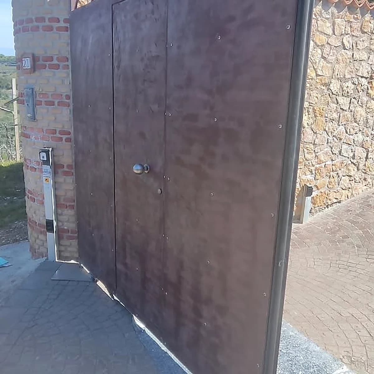 Portone in ferro verniciato effetto corten su una parete esterna in pietra